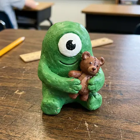 A clay monster hugging a teddy bear